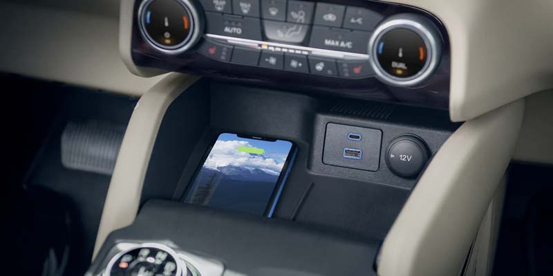 Smartphone charging wirelessly on a car's center console with USB ports