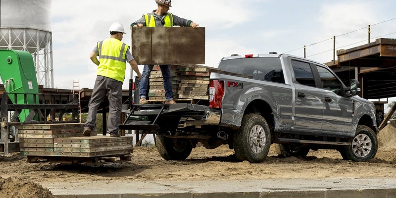 Gray Ford Super Duty truck being loaded by construction workers at a job site