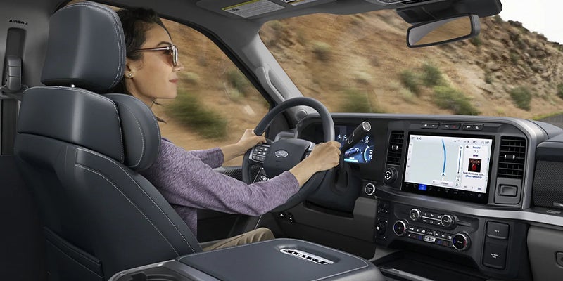 Woman driving a truck, looking forward, with navigation displayed on the center screen