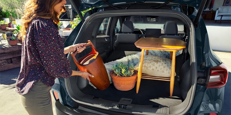 Woman loading items into an open Ford Escape trunk.