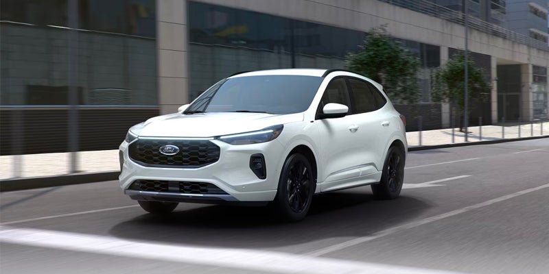 A white Ford Escape SUV driving on a city street with dark whe